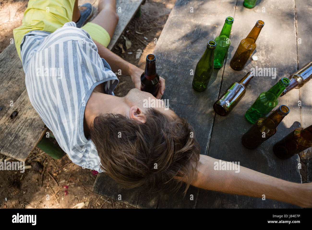unconscious-drunk-man-lying-on-a-bench-in-the-park-J84E7P.jpg