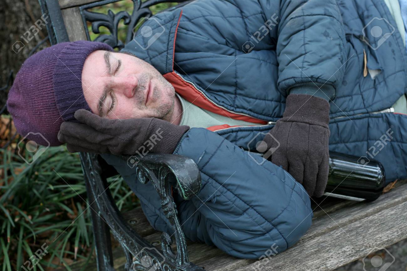 337525-a-homeless-man-asleep-on-a-park-bench-with-a-bottle-of-wine-in-his-hand-.jpg